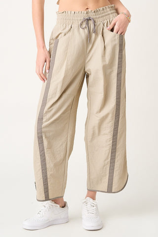 Beige pants with gray stripes worn by a person on a white background