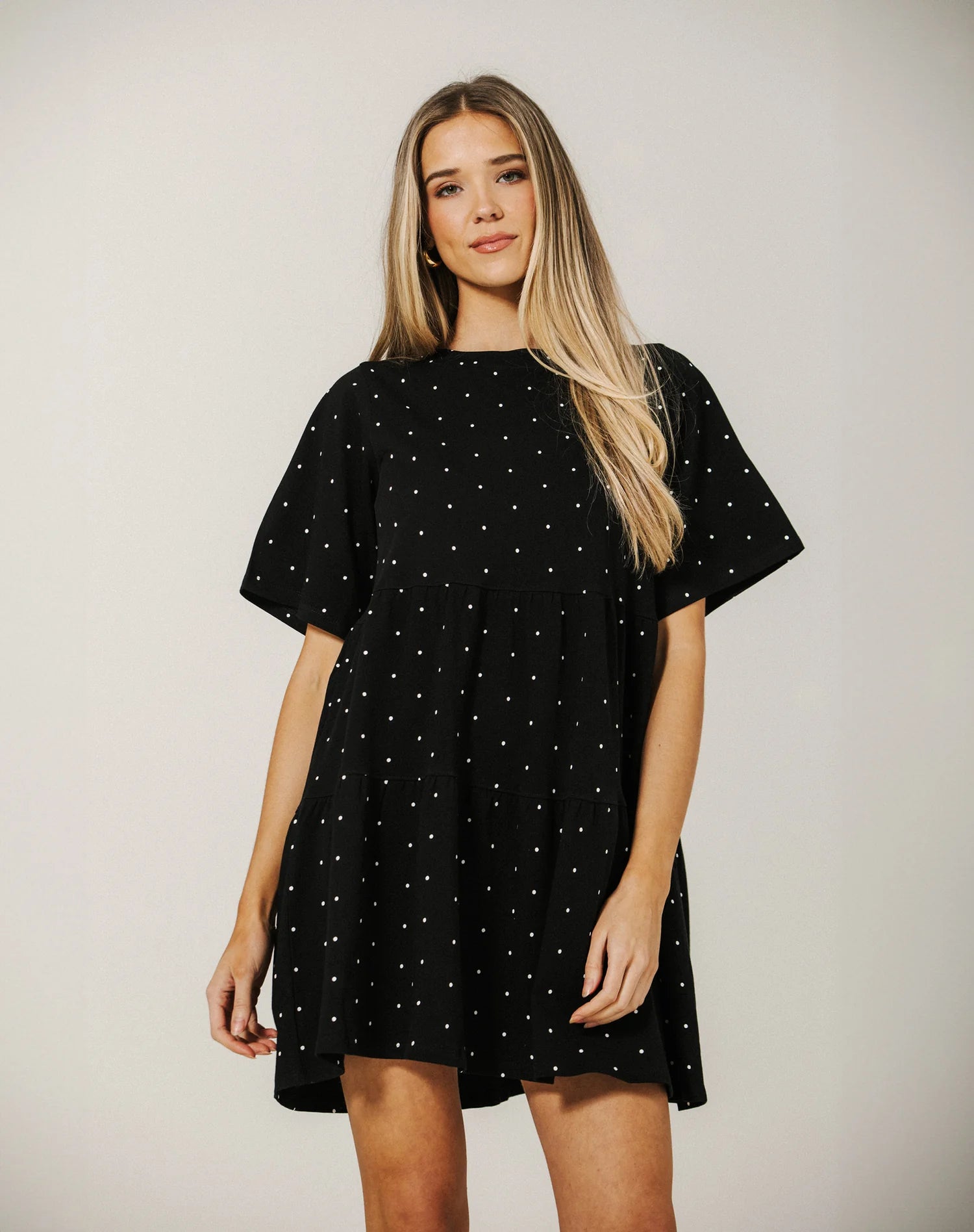 Woman wearing a black dress with white polka dots against a plain background