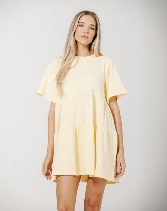 Woman wearing a light yellow dress against a plain background