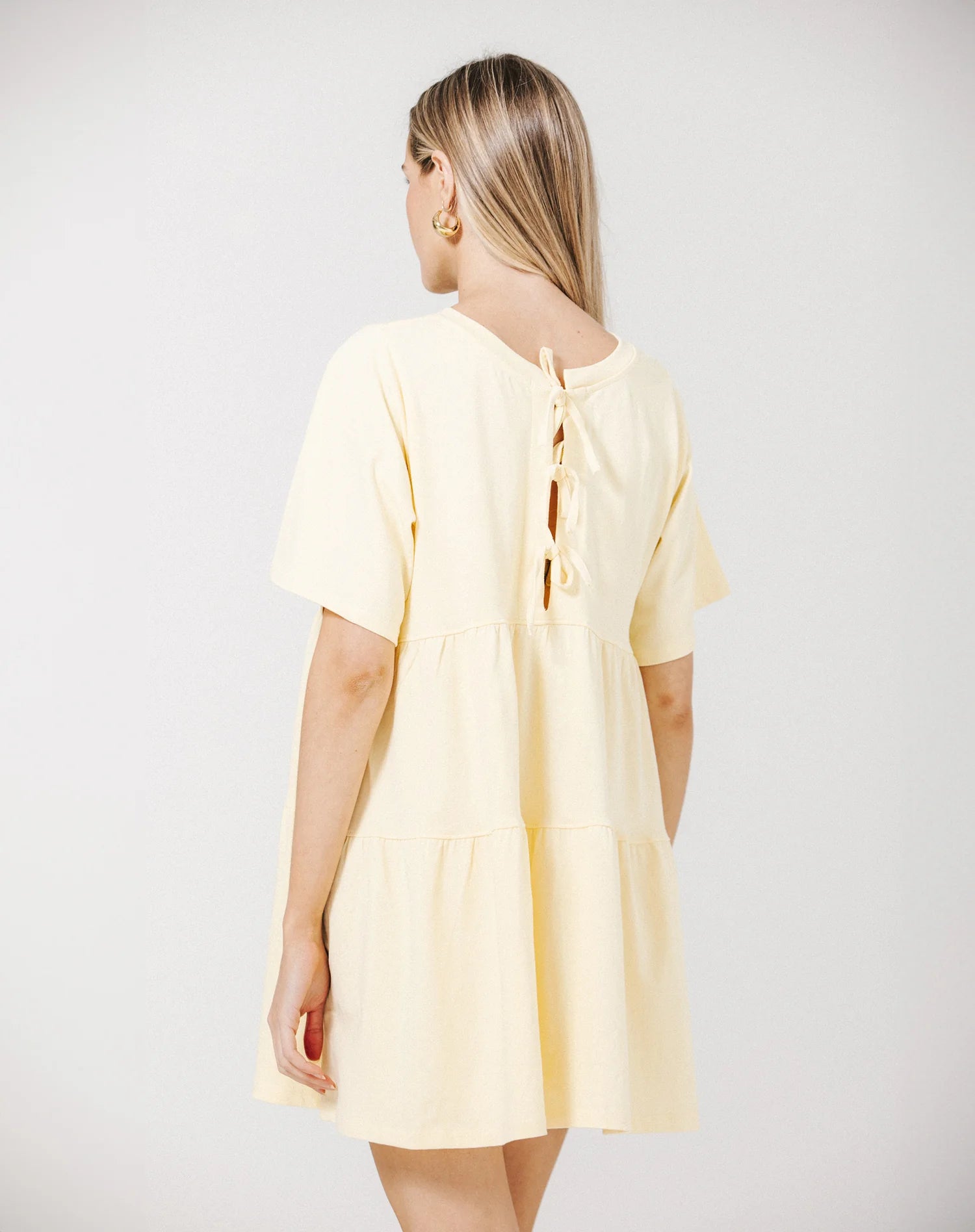 Woman wearing a light yellow dress on a plain background