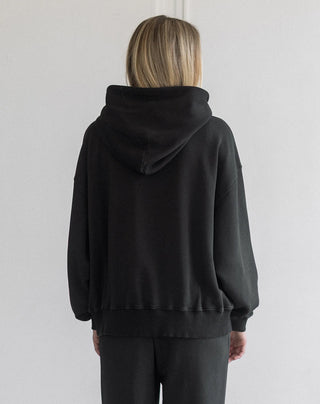 Women modelling an oversized hoodie against a neutral photo backdrop. 