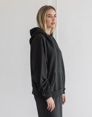 Women modelling an oversized hoodie against a neutral photo backdrop. 