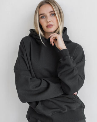 Women modelling an oversized hoodie against a neutral photo backdrop. 