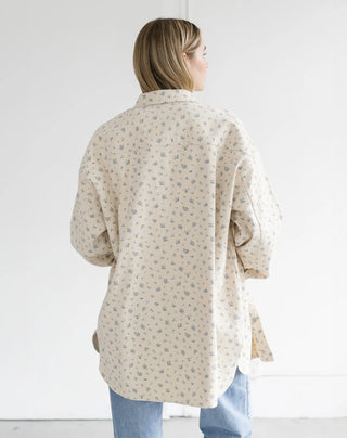 women wearing a blue floral denim jacket with blue jeans and white top on a plain background.