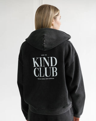 Person wearing a black hoodie with 'Kind Club' text on the back against a white background