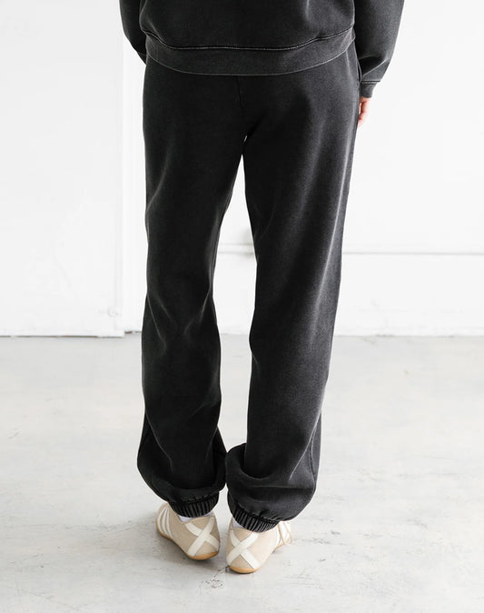 Person wearing black sweatpants and a matching top on a white background