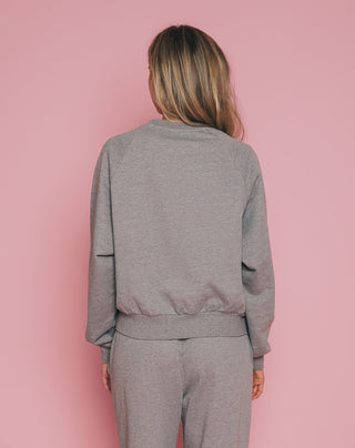 Person wearing a gray tracksuit against a pink background
