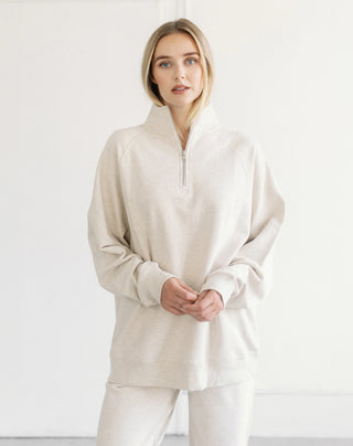 Women modelling a 1/2 zip oversized sweater against a neutral photo back drop.