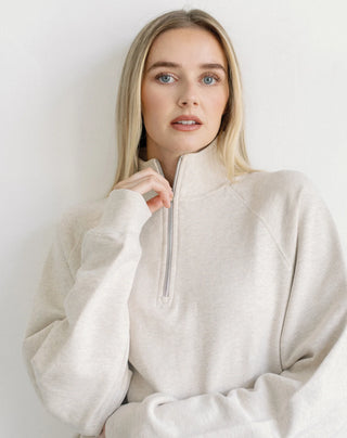 Women modelling a 1/2 zip oversized sweater against a neutral photo back drop.