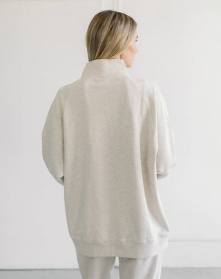 Women modelling a 1/2 zip oversized sweater against a neutral photo back drop.