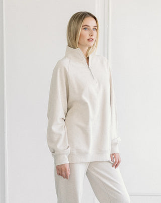 Women modelling a 1/2 zip oversized sweater against a neutral photo back drop.