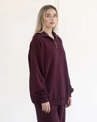 Women modelling a 1/2 zip oversized sweater against a neutral photo back drop.