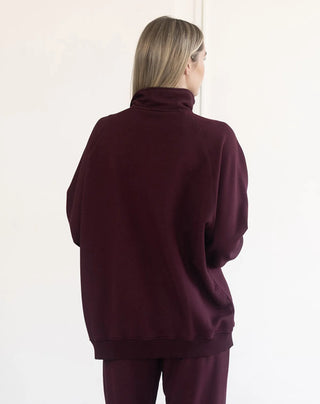 Women modelling a 1/2 zip oversized sweater against a neutral photo back drop.