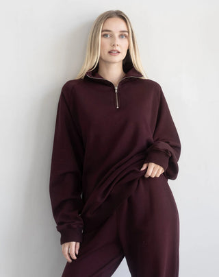 Women modelling a 1/2 zip oversized sweater against a neutral photo back drop.
