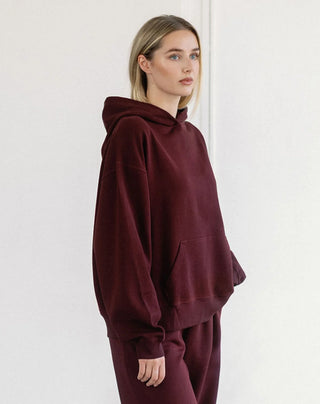 Women modelling an oversized hoodie against a neutral photo backdrop. 