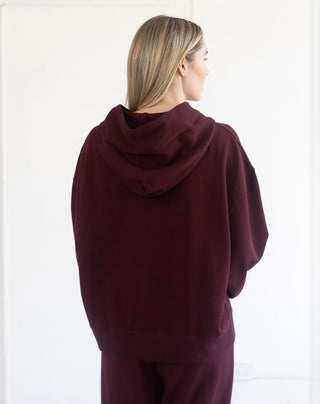 Women modelling an oversized hoodie against a neutral photo backdrop. 