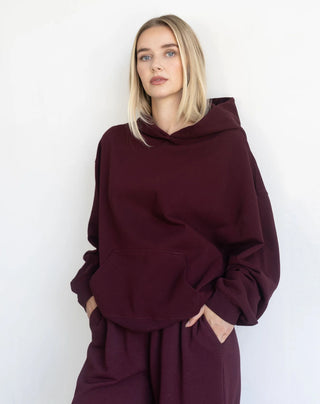 Women modelling an oversized hoodie against a neutral photo backdrop. 