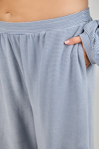 Close-up of a person wearing blue and white striped pajama pants with a plain background.