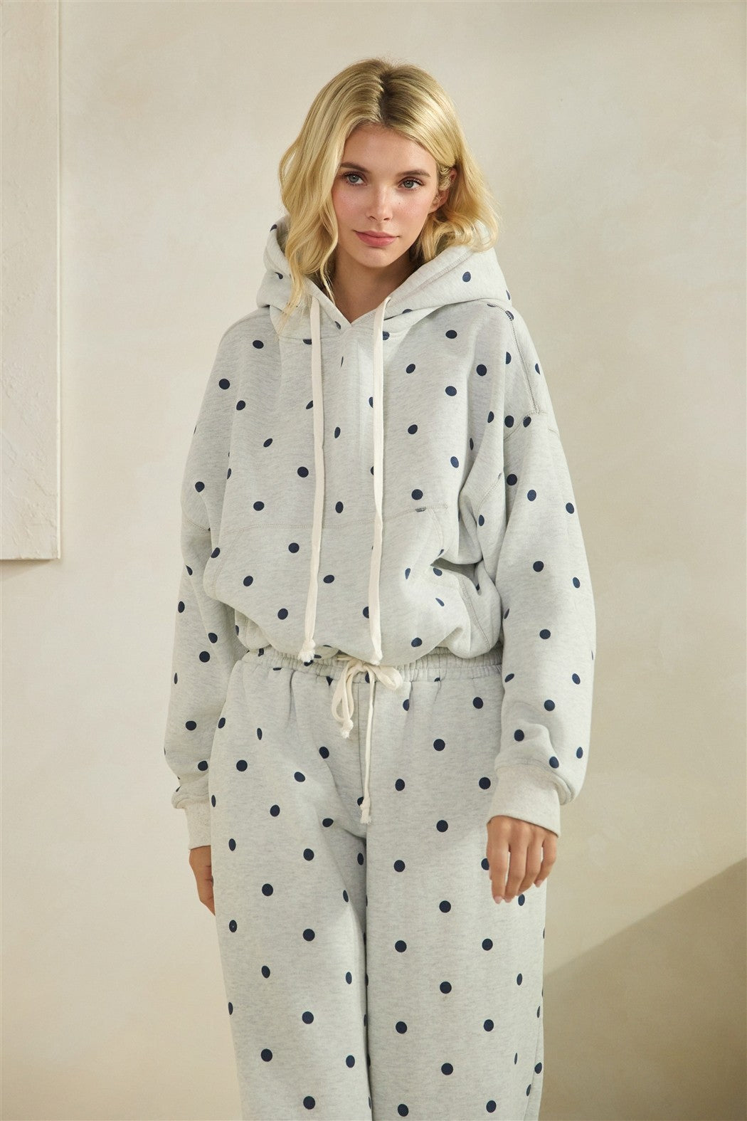 Woman wearing a polka dot hoodie and pants set against a plain background