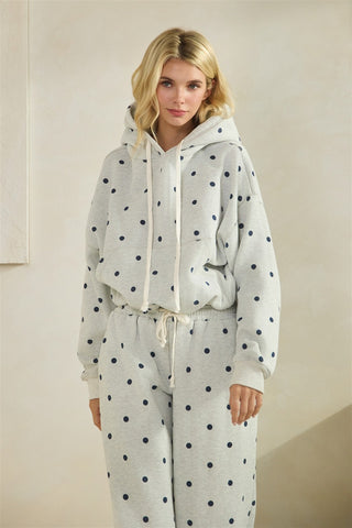 Woman wearing a polka dot hoodie and pants set against a plain background