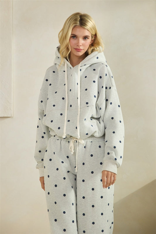 Woman wearing a polka dot hoodie and pants set against a plain background