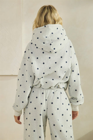 Person wearing a polka dot hoodie and pants in a neutral setting