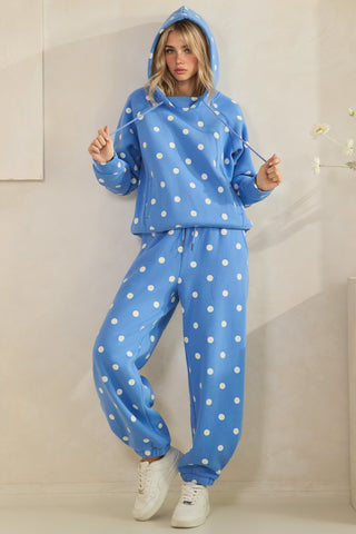 Person wearing a blue polka dot hoodie and pants set against a neutral background