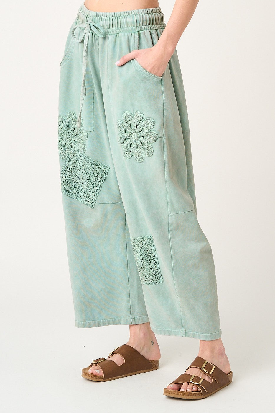 Light blue pants with floral embroidery on a white background
