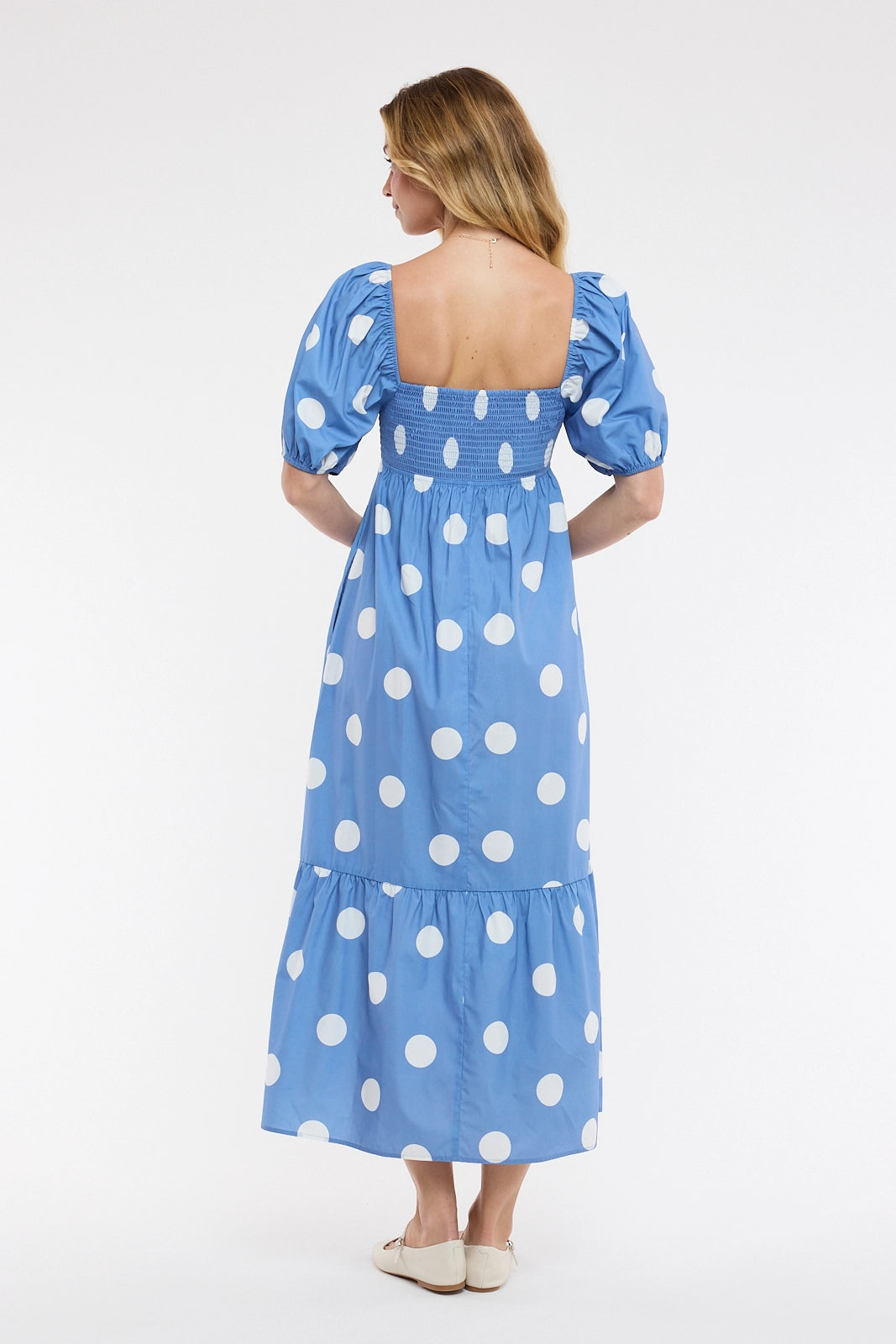 Woman wearing a blue polka dot dress on a white background