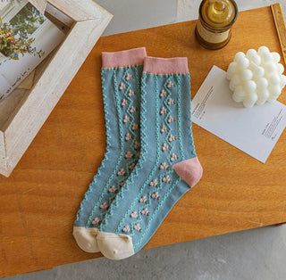 Pair of blue socks with pink accents on a wooden surface