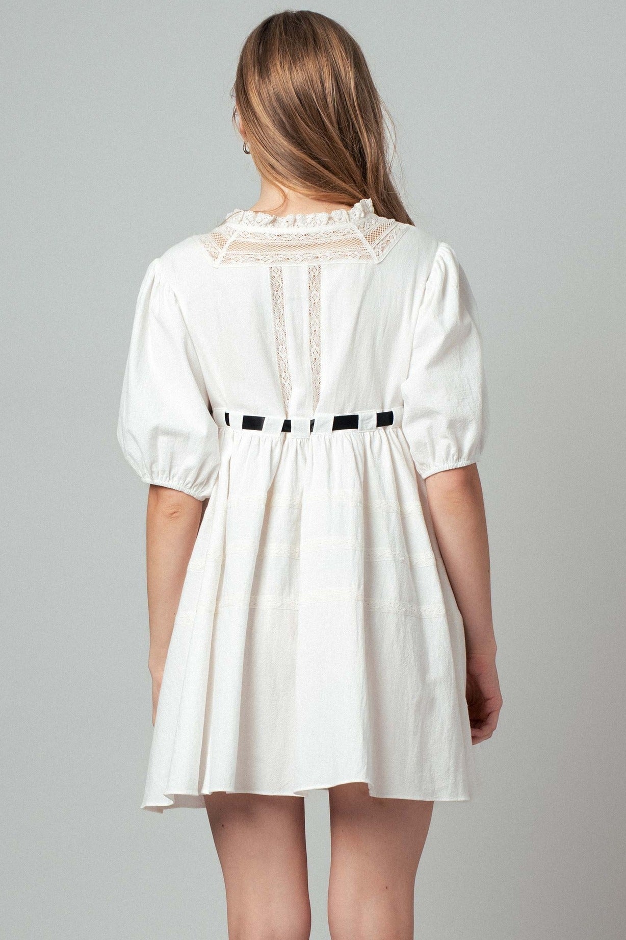 White dress with lace details on a gray background