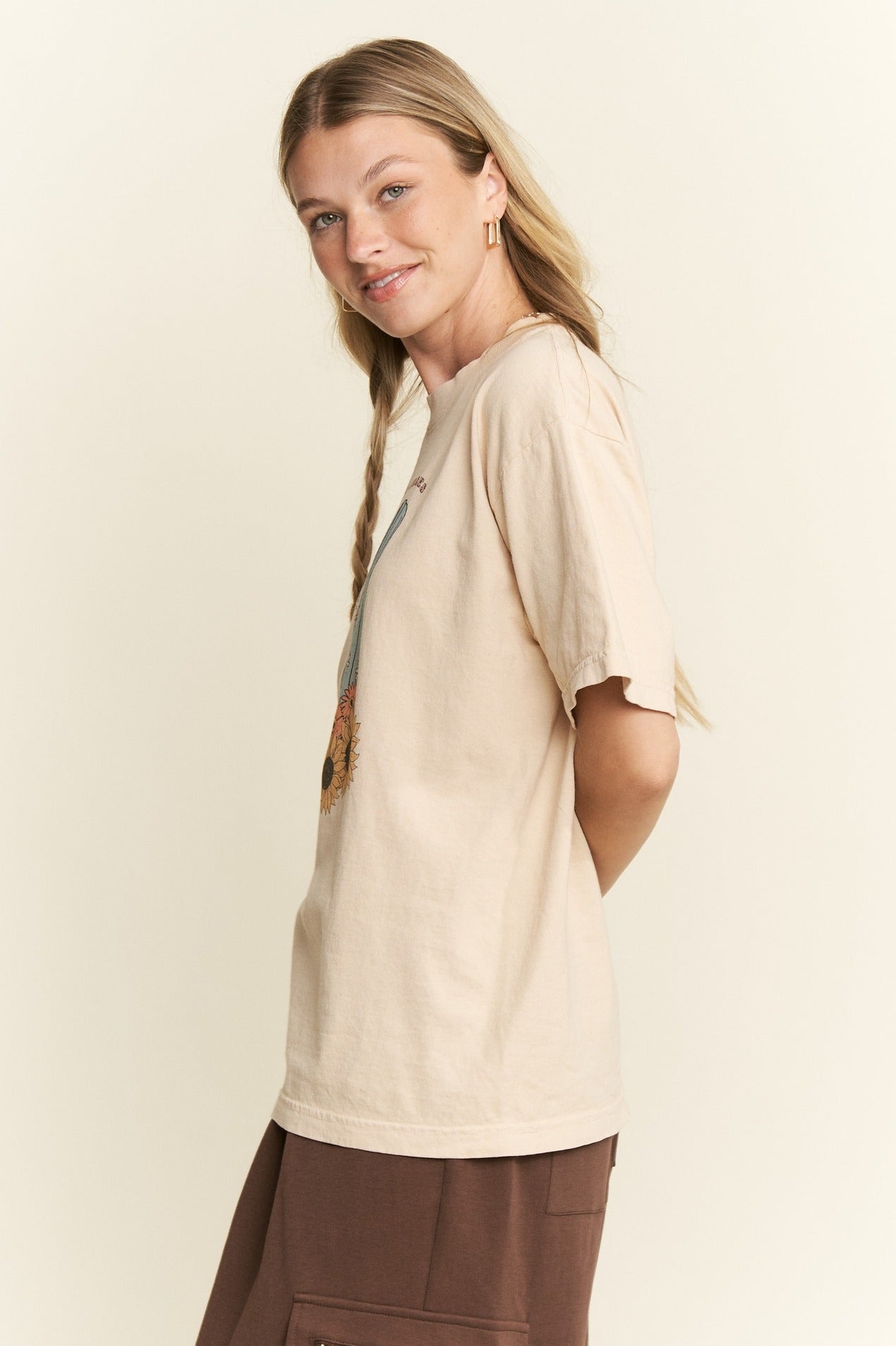 Woman wearing a beige t-shirt with a plain background