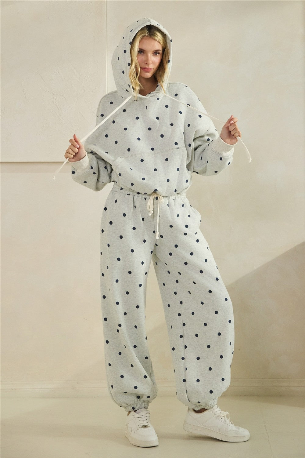 Grey pants with black polka dots worn by a person on a beige background