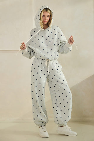 Grey pants with black polka dots worn by a person on a beige background