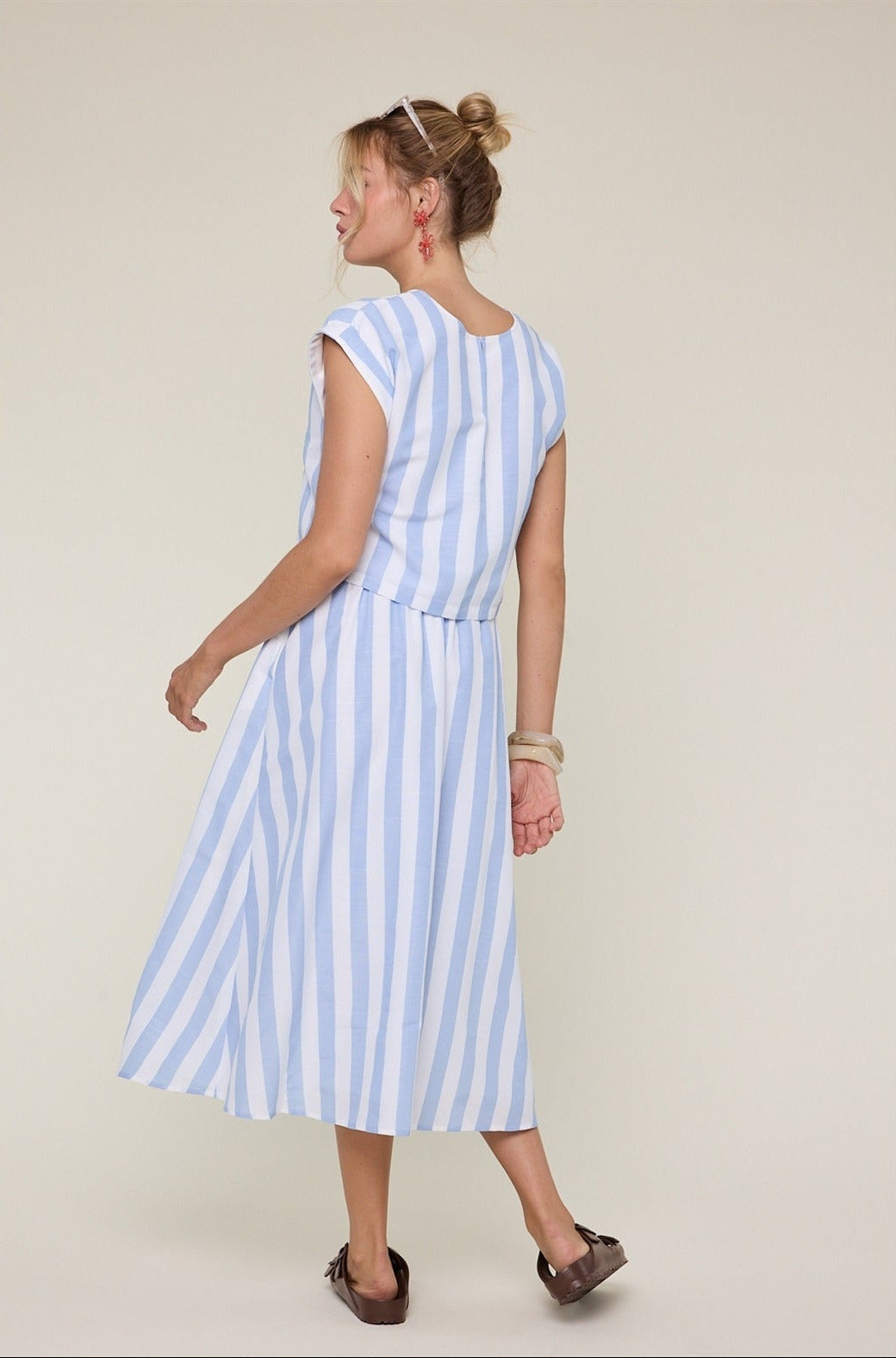 Woman wearing a blue and white striped dress on a plain background