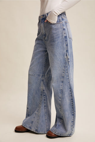Person wearing blue jeans on a plain background