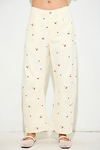 White pants with red cherry pattern worn by a person on a white background