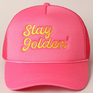 Pink cap with yellow 'Stay Golden' text on a beige background
