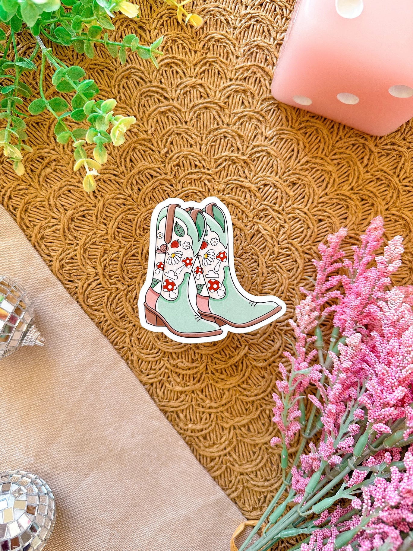 Decorative sticker of floral cowboy boots on a textured surface with flowers and a candle.