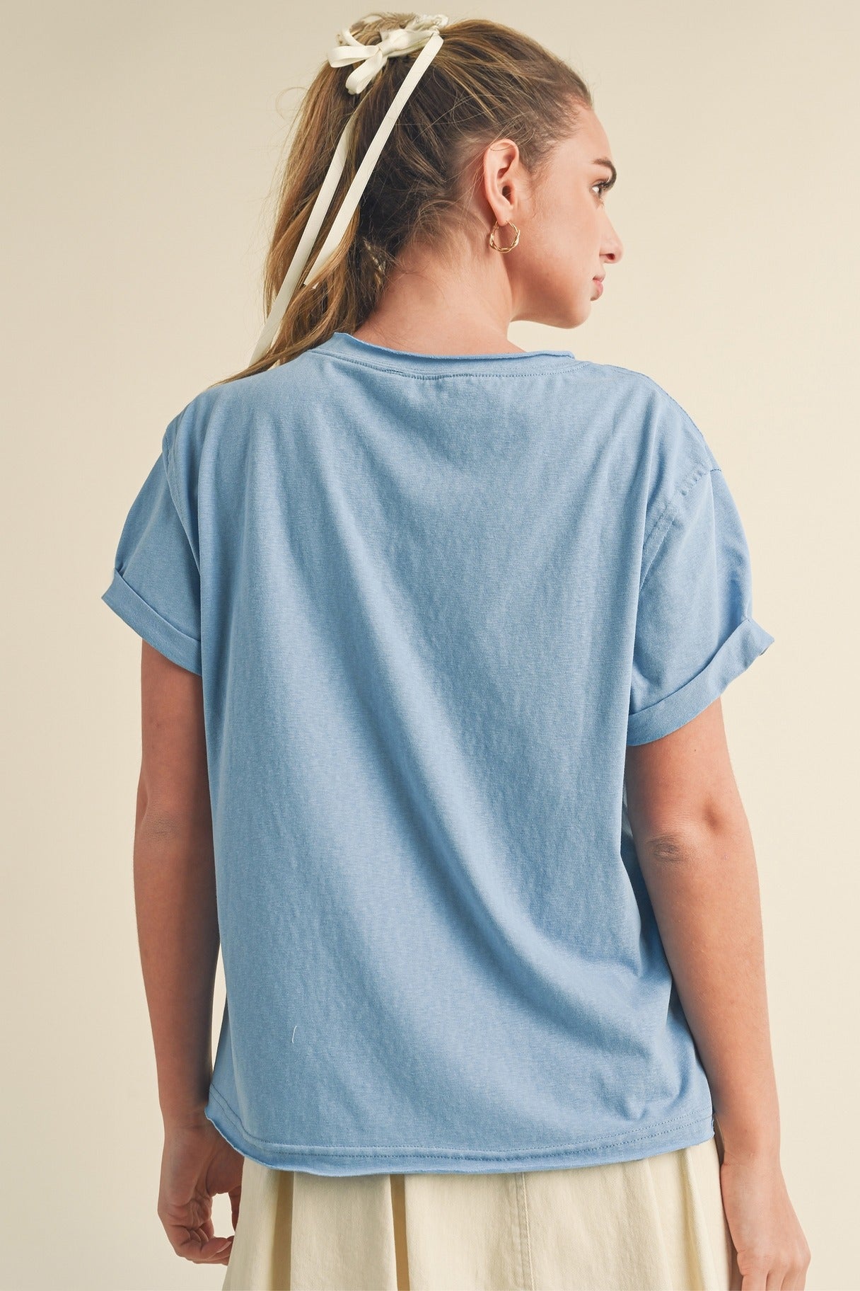 Woman wearing a light blue t-shirt on a beige background