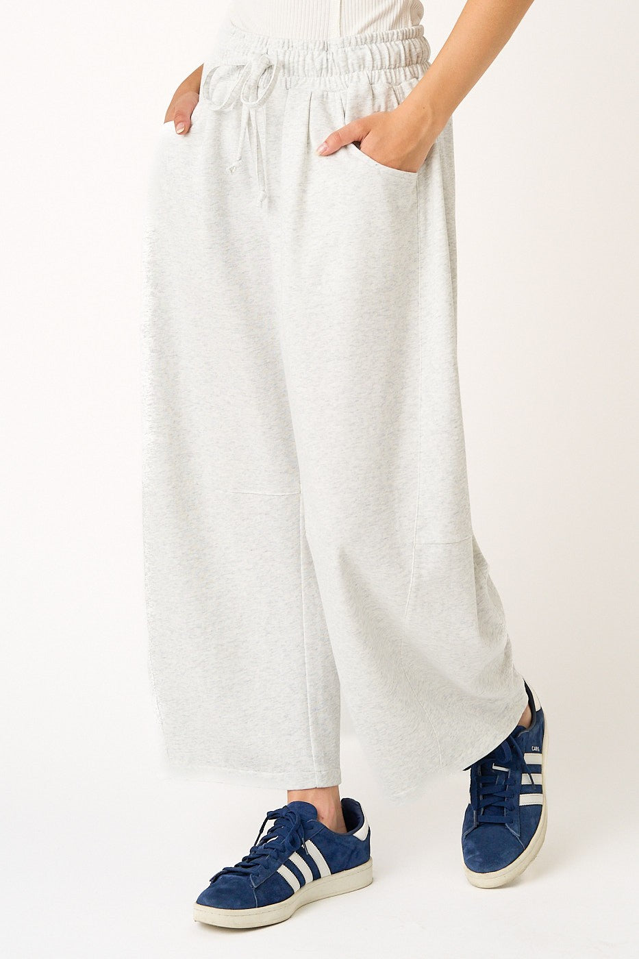 Person wearing white pants and blue sneakers on a white background