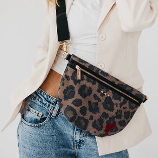 A leopard-print fanny pack with black trim and a red heart accent, worn crossbody over a cream blazer and blue jeans.