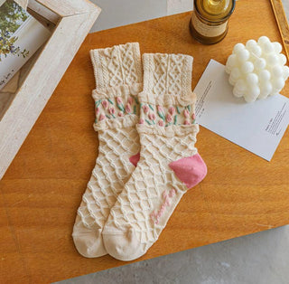 Pair of beige socks with pink hearts on a wooden surface