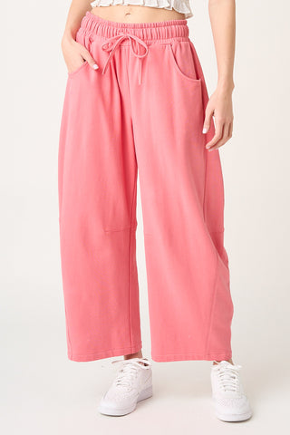 Person wearing pink wide-leg pants with a white background
