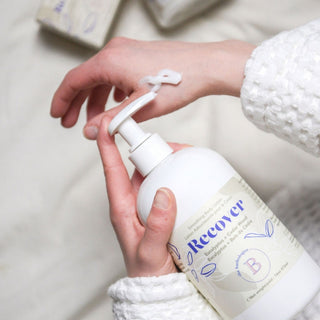 Person holding a bottle labeled 'Recover' with a blurred background