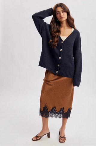 Women wearing a navy cardigan against a neutral background.