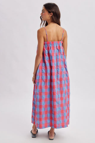 A woman modeling a sleeveless midi dress with thin straps and a pink and blue gingham pattern, shown from the back against a light gray studio background.