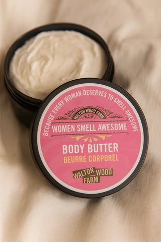 Body butter jar with pink label on a beige fabric background
