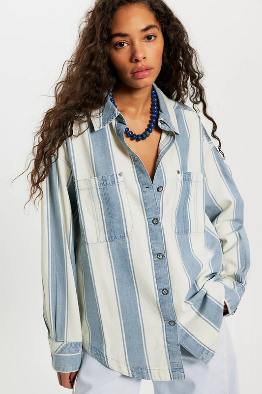 Woman wearing a blue and white striped shirt with a necklace on a white background
