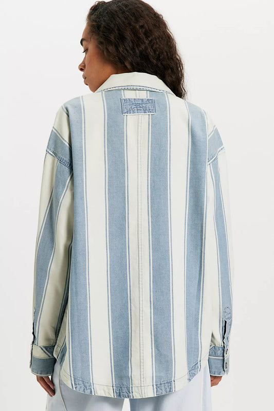 Person wearing a blue and white striped denim jacket on a white background